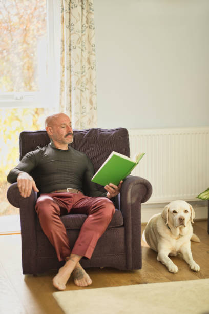 istock Middle aged man relaxing at home with a book and his dog 2177836022