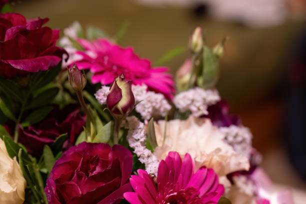 A close-up of a romantic floral bouquet featuring deep red roses, a bright pink gerbera daisy, and soft white flowers. The arrangement captures the elegance and beauty of fresh blooms, perfect for special occasions.