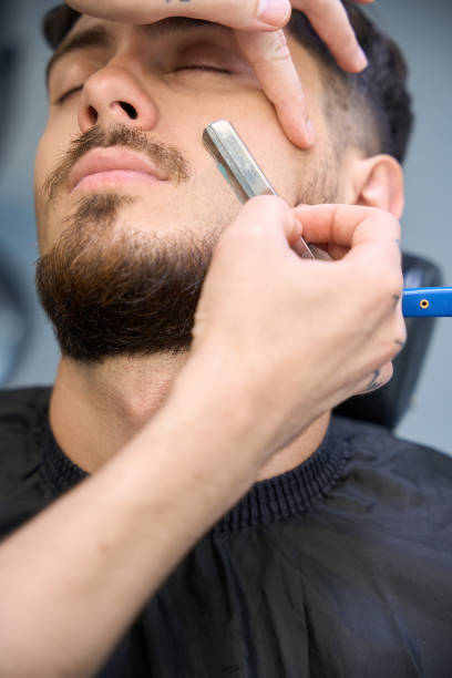 istock Stylist trims beard with fine razor for clean lines 2177842702