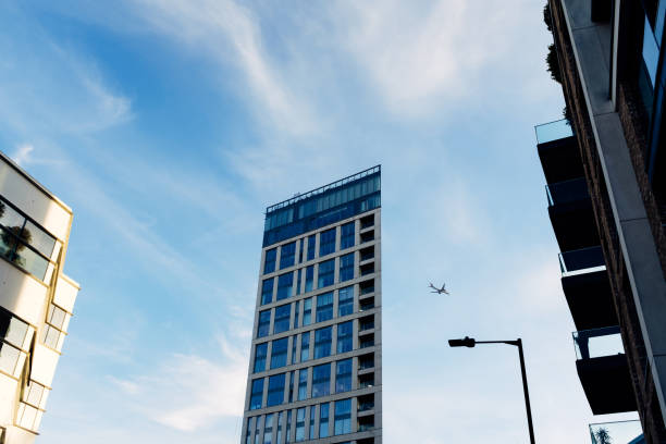 istock Airplane flying over modern glass skyscraper building facade under blue sky 2177844595