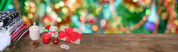 hot cocoa, wooden table, New Year's presents, stack wool sweaters, blurred colorful Christmas tree decorations, blur background panorama, christmastime Moments