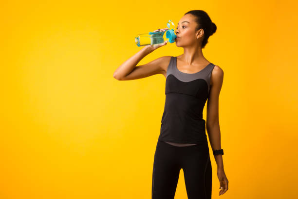 istock Woman In Sportswear Drinking Water Standing In Studio 2177851369