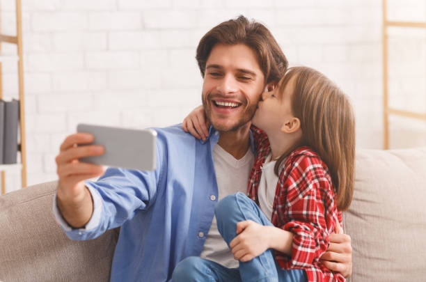 istock Little daughter kissing daddy while taking selfie together 2177853880