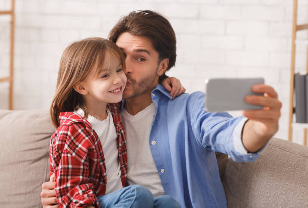 istock Dad kissing little daughter while taking selfie together 2177853887