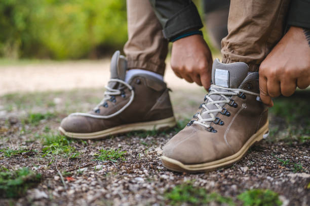 istock Man tying hiking boots on a grassy path in outdoor setting 2177854788