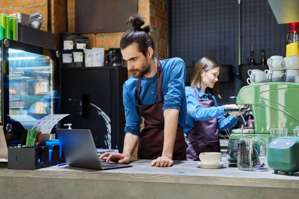 istock Two cafe workers working together behind counter, at coffee shop 2177855081
