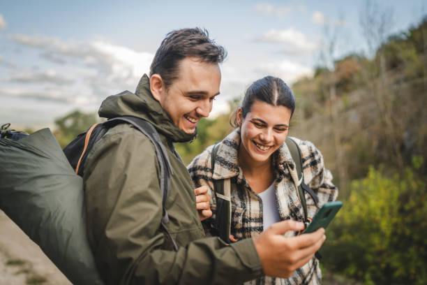 istock Cheerful couple take a break from hiking and use mobile phone together 2177855348