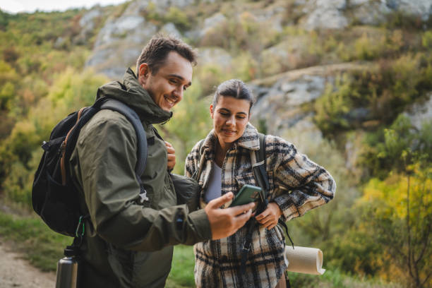 istock Cheerful couple take a break from hiking and use mobile phone together 2177855494