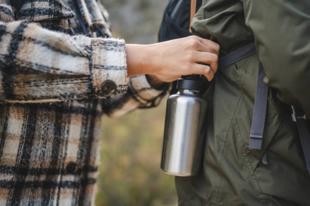 istock close up of woman hands put water bottle on mans backpack 2177855721
