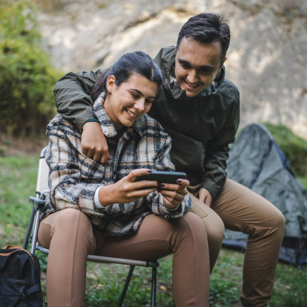 istock happy couple campers sit and use mobile phone for fun in front tent 2177855964