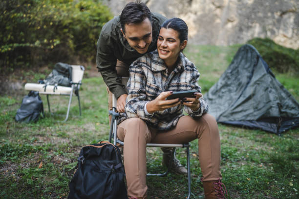istock happy couple campers sit and use mobile phone for fun in front tent 2177856903