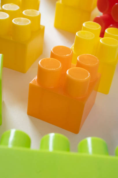 Brightly colored toy building blocks arranged in a playful pattern. The blocks come in vibrant shades of orange, yellow, and green, ideal for children’s educational play.