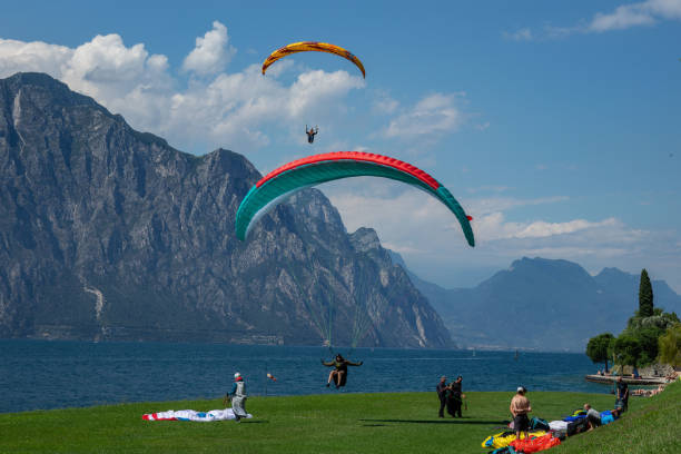 17th June 2024: Grass landing strip in Malcesine, beside Lake Garda. for paragliders who have taken off from the top of the mountain nearby. They are taking turns to land on the narrow strip of grass at the water's edge.