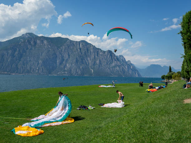 17th June 2024: Paragliders packing up on a grass landing strip in Malcesine, beside Lake Garda. The adventurous flyers have taken off from the top of the mountain nearby and are taking turns to land on the narrow strip of grass at the water's edge. People pack up quickly to free up the space for the next person.