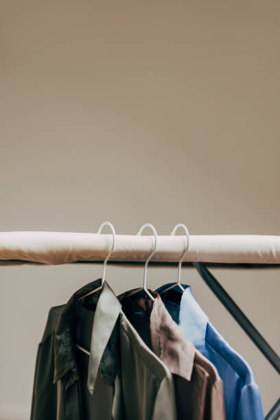 A neatly arranged collection of shirts in various colors hangs on an ironing board.