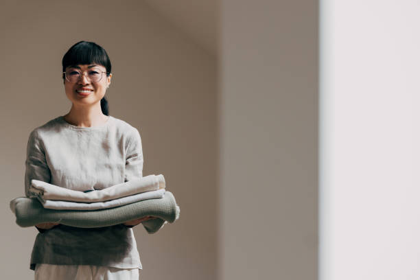 istock Smiling Woman Holding Folded Linens in Minimalist Setting 2177864477