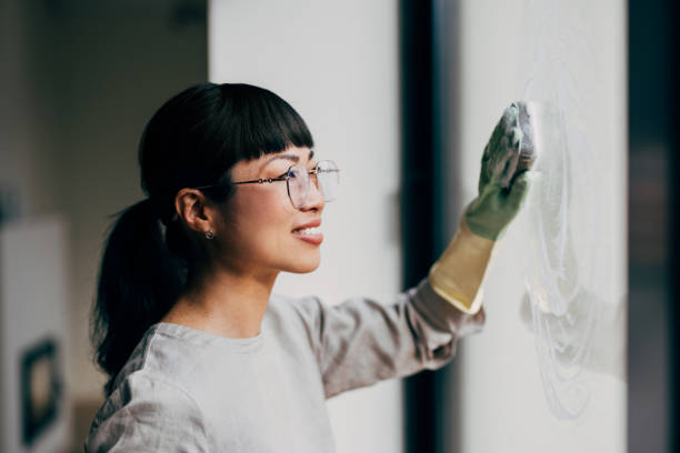 istock Woman Smiling While Cleaning a Window with Gloved Hands 2177864519