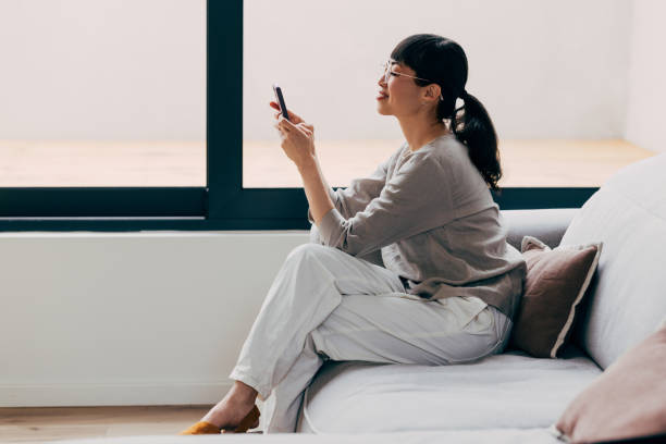 istock Young Woman Relaxing on Couch Using Smartphone Indoors 2177864545