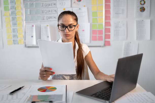 istock Hispanic woman with accounting bookkeeping documents checking financial data or report working in office with laptop. 2177874534