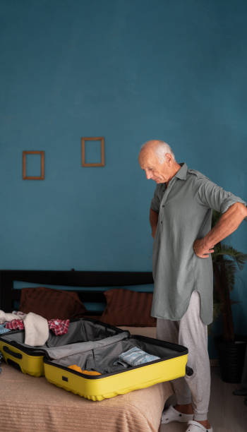 istock Mature man stands thoughtfully near an open suitcase packing his luggage getting ready for a trip 2177874964