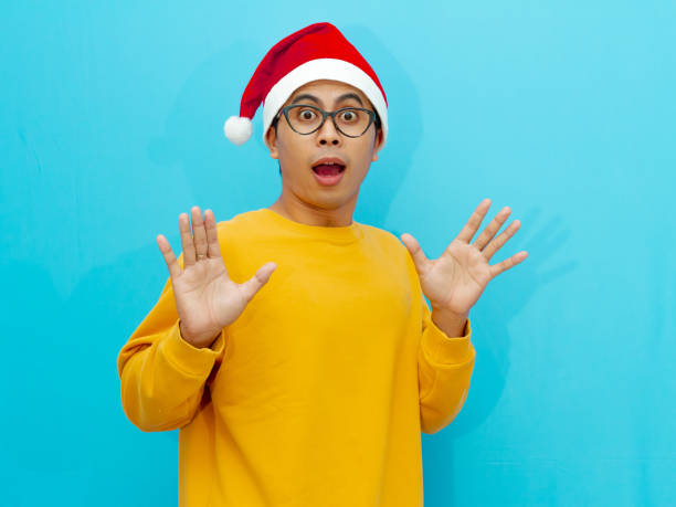 istock Excited young Asian man in a Christmas hat showing a surprised expression while looking at the camera. 2177882793