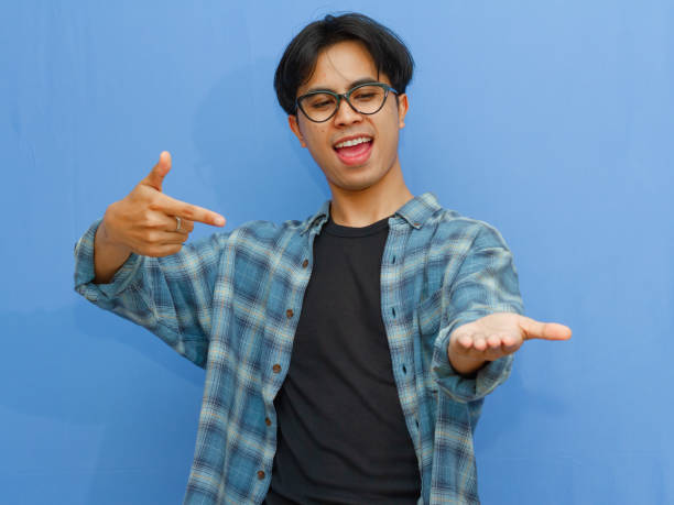 istock Attractive Asian man smiling while pointing to his open hand palm 2177884671