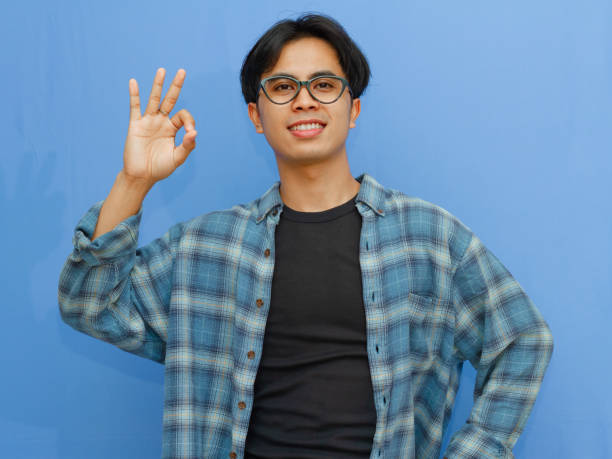 istock Young asian man showing ok hand sign and smiling while standing over isolated blue background, Happy asia male showing ok hand, Positive people gesture 2177885274