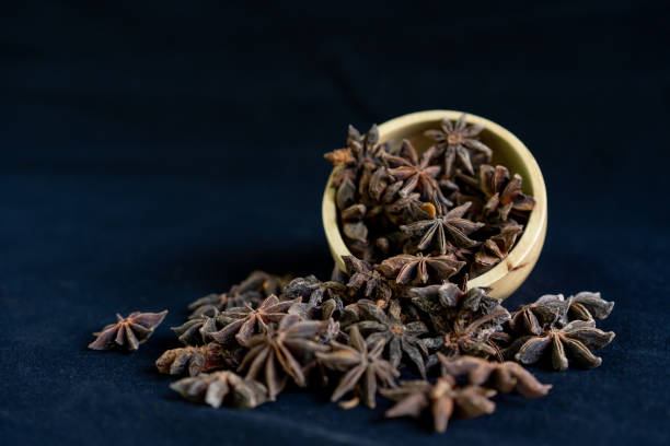 Chinese anise in wooden container on black background