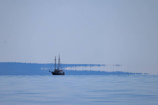 A sailing ship at sea with a mirage on the horizon