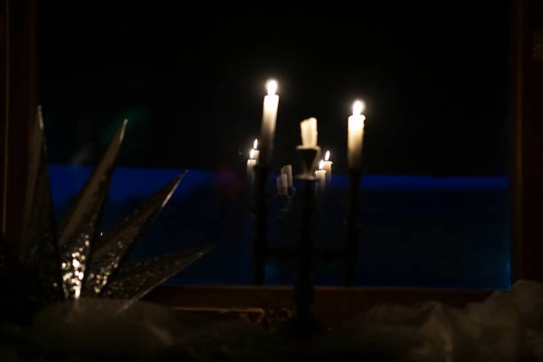 Candles  placed in a candelabra, on a windowsill in a dark room