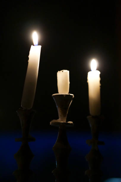 Candles  placed in a candelabra, on a windowsill in a dark room