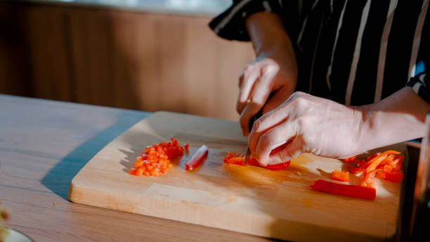istock Young Asian man cutting red pepper while watching cooking class on laptop screen. 2177897636