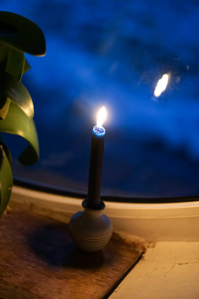Candles  placed in a candelabra, on a windowsill in a dark room