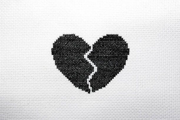 istock A broken heart is embroidered with black threads on white fabric. 2177905726