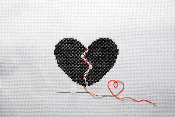 istock A broken heart is embroidered with black threads on white fabric. 2177905748