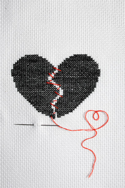 istock A broken heart is embroidered with black threads on white fabric. 2177905769