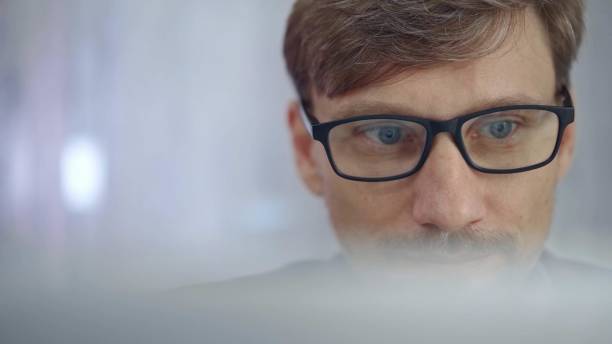 istock Businessman with glasses looking intently obscured partially by a translucent surface of laptop. Business people concept 2177905783