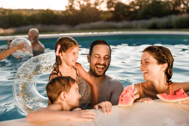 istock Happy family talking while eating watermelon in the pool. 2177905879