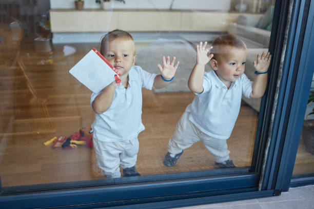 A cute toddler with curly hair peers through a glass door, filled with curiosity. The cozy home interior and soft lighting create a warm and joyful atmosphere.