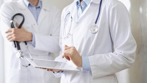 istock Two doctors wearing white coats and stethoscopes, using a digital tablet, discussing a patient's medical history. Medicine and science 2177908176