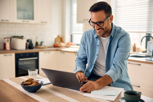 istock Happy man working on laptop in the kitchen. 2177911321