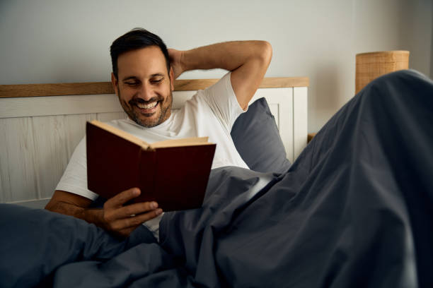 istock Happy man reading book in bed. 2177911632
