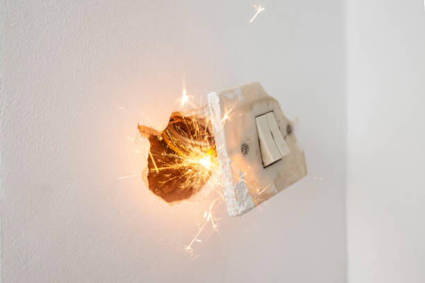 istock Short circuit sparks and flame in a striped broken outlet on a white wall background , short circuit concept 2177913568