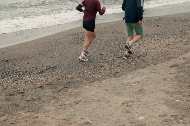 Group of people running on beach with cityscape in background. May 4, 2025 Constanta Romania.