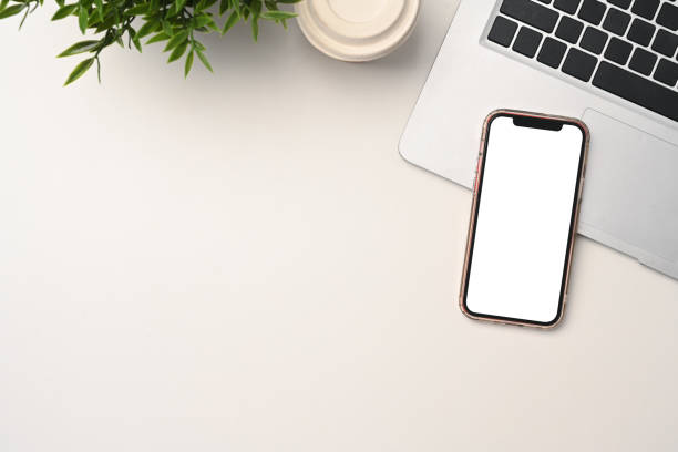 istock Mobile phone with blank screen, laptop, and paper cup of coffee on white table 2177923029