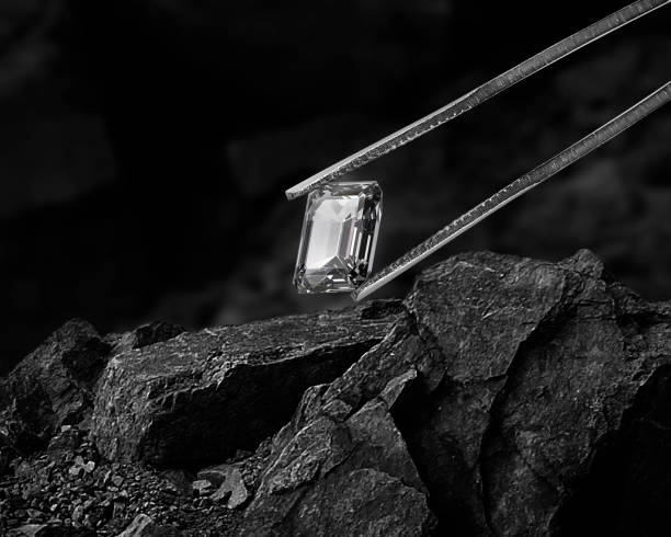 Cut Beautiful diamond held by tweezers on black coal background