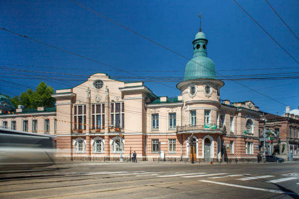 istock This photograph showcases a historic building with elegant architecture. The structure has a light pink façade with white detailing, large arched windows, and a prominent dome roof painted in a distinctive green hue. 2177929124