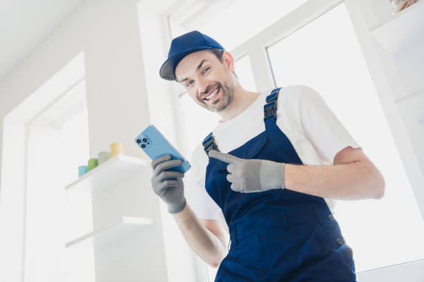 istock Smiling handyman in overalls using smartphone during home renovation project in bright modern room 2177929499