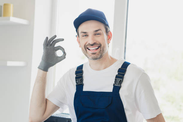 istock Friendly handyman in blue overalls giving an OK gesture while standing in a bright modern room during home renovation 2177929530