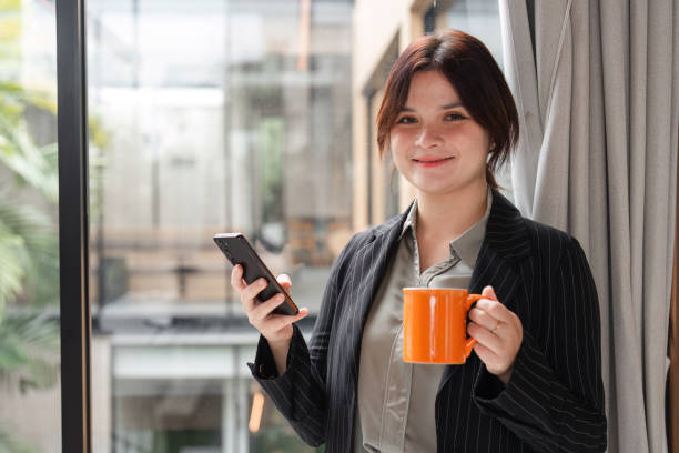 istock Confident Business Woman Using Smartphone in Modern Office Setting with Natural Light and Professional Attire 2177930570